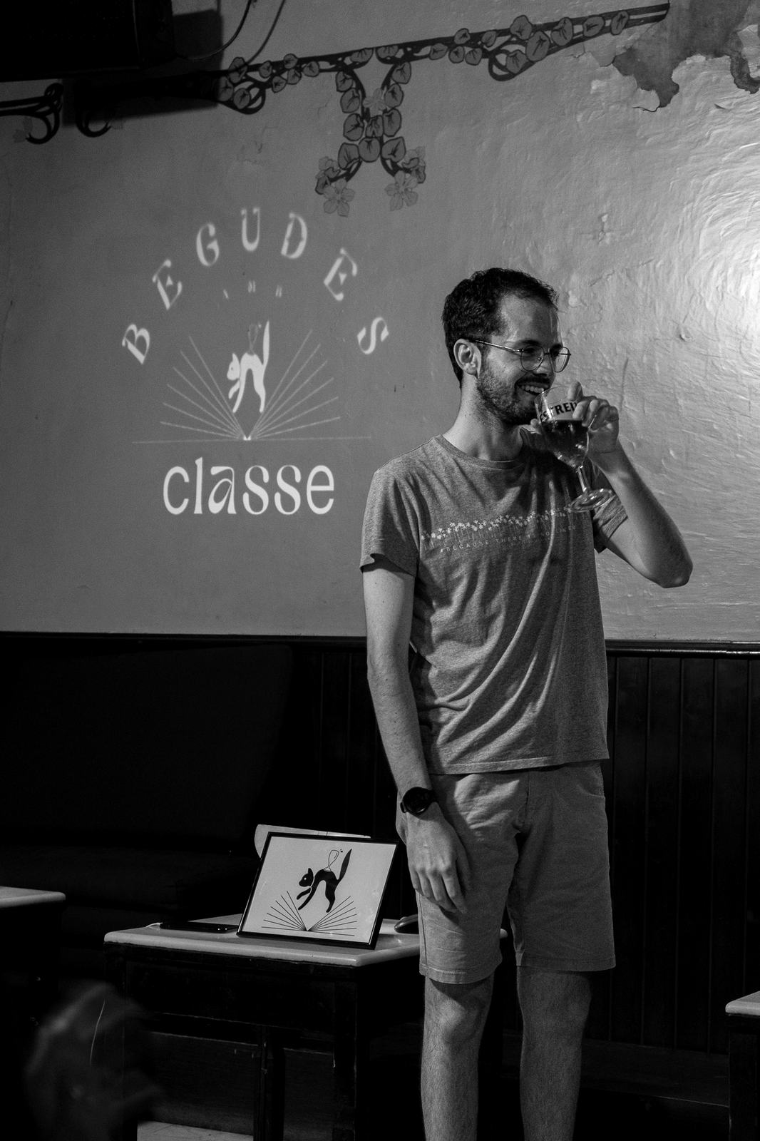 Toni Bertólez amb una copa a la mà davant del logotip projectat