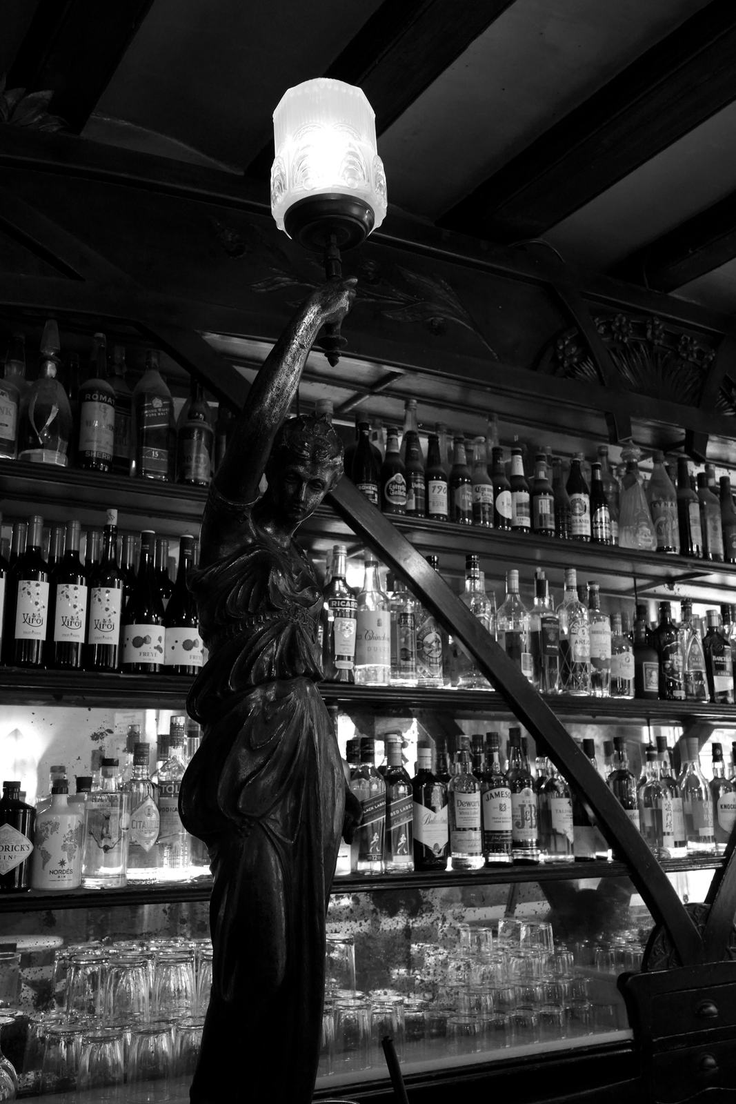 Escultura modernista amb làmpada davant de les ampolles de la barra