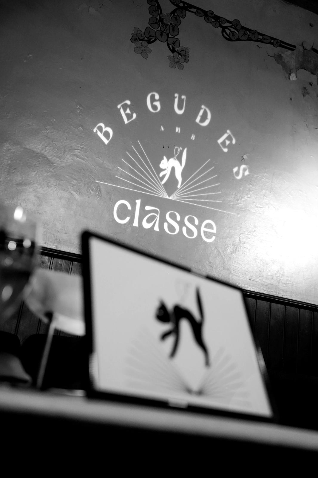 El logotip de Begudes amb classe projectat a la paret del bar