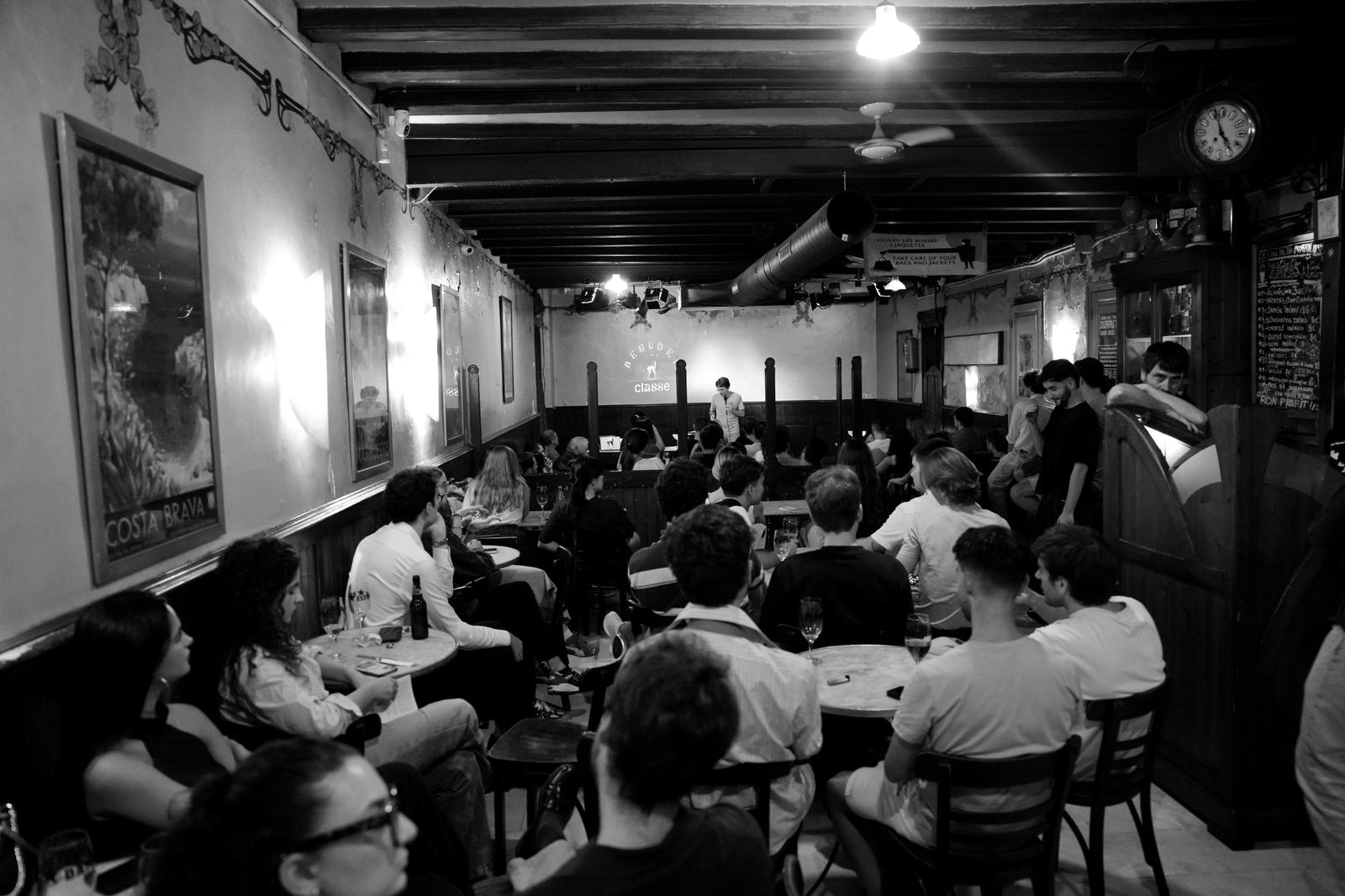 La sala de la Casa Almirall plena de gent escoltant el ponent al fons, amb el logotip projectat a la paret